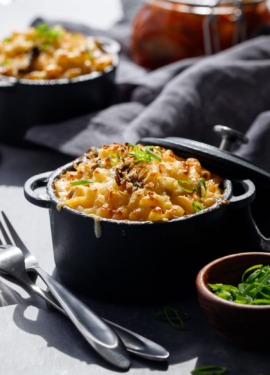 Creamy white cheddar Macaroni & Cheese with Kimchi in black ramekins with sliced scallion