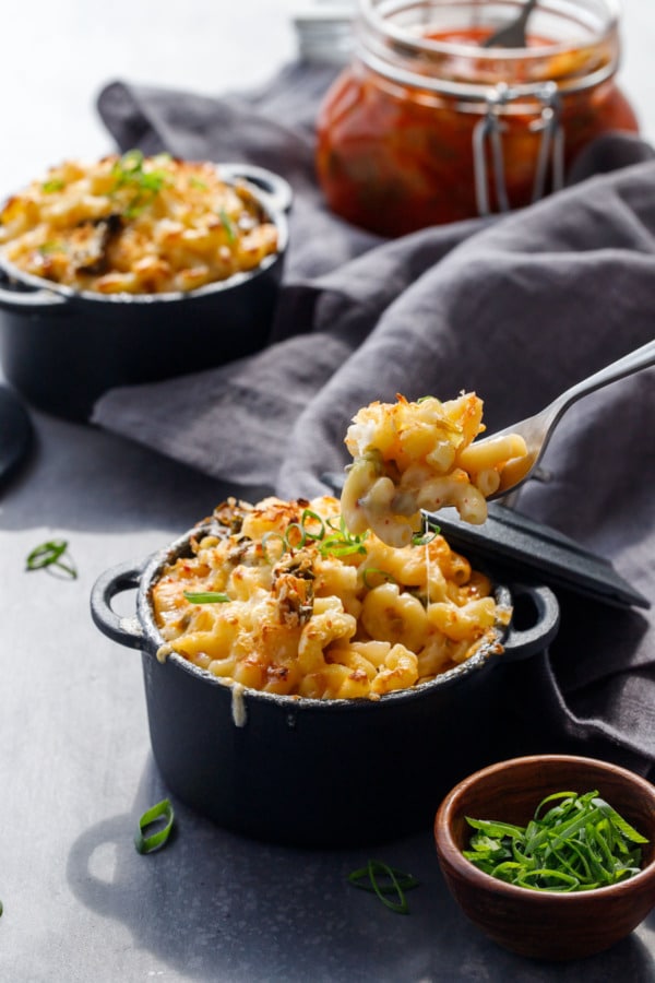 Forkful of Kimchi Mac 'n Cheese in a black ramekins with scallions