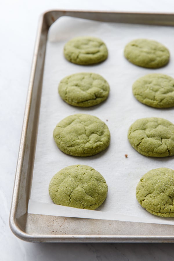 Baked matcha sugar cookies on a parchment-lined baking sheet