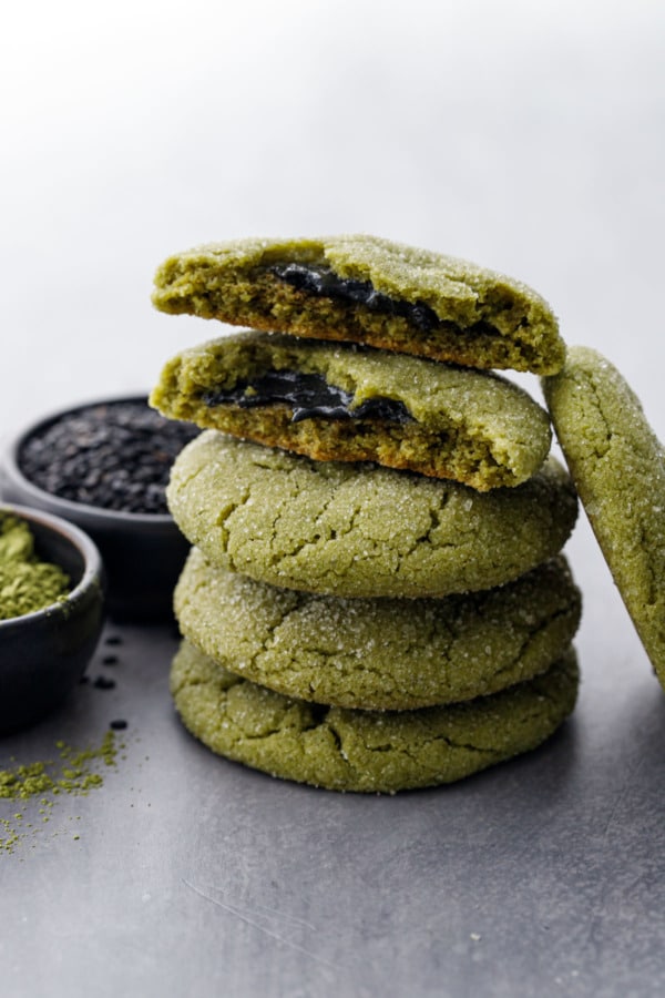 Stack of Black Sesame-Stuffed Matcha Sugar Cookies, with bowls of matcha powder and black sesame seeds