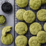 Overhead shot with a cooling rack with rows of matcha sugar cookies, bowls of matcha powder and black sesame seeds.