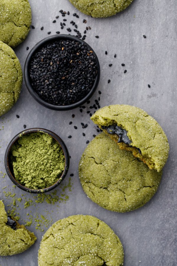 Black Sesame-Stuffed Matcha Sugar Cookies and bowls of black sesame seeds and matcha powder on a gray background