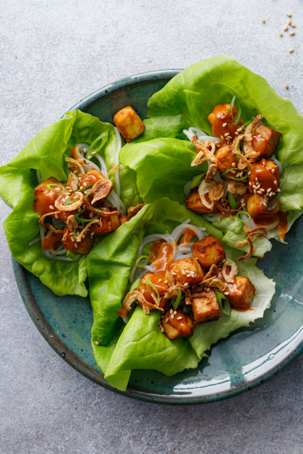 Overhead shot of Baked Tofu Lettuce Wraps with Spicy Peanut Sauce on a turquoise plate