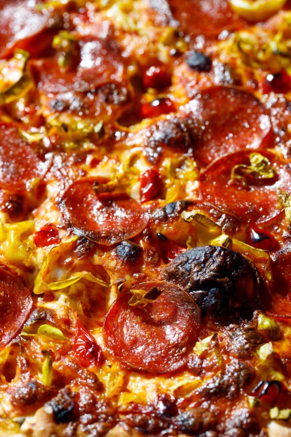 Closeup of toppings and blackened bubbles on a pan pizza.