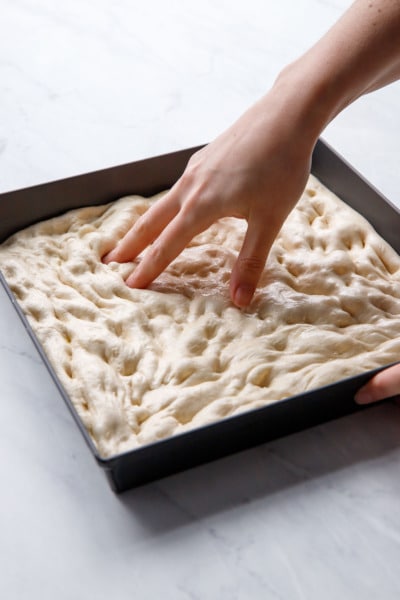 Pressing the pizza dough into the baking pan with your fingers