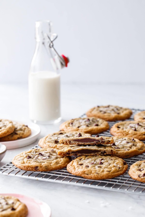 Ganache-Stuffed Chocolate Chip Cookies on a wire rack with a glass milk bottle