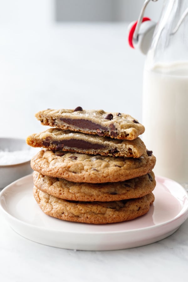 Stack of cookies, one cut in half to show the ganache filling, with a milk bottle in the background.