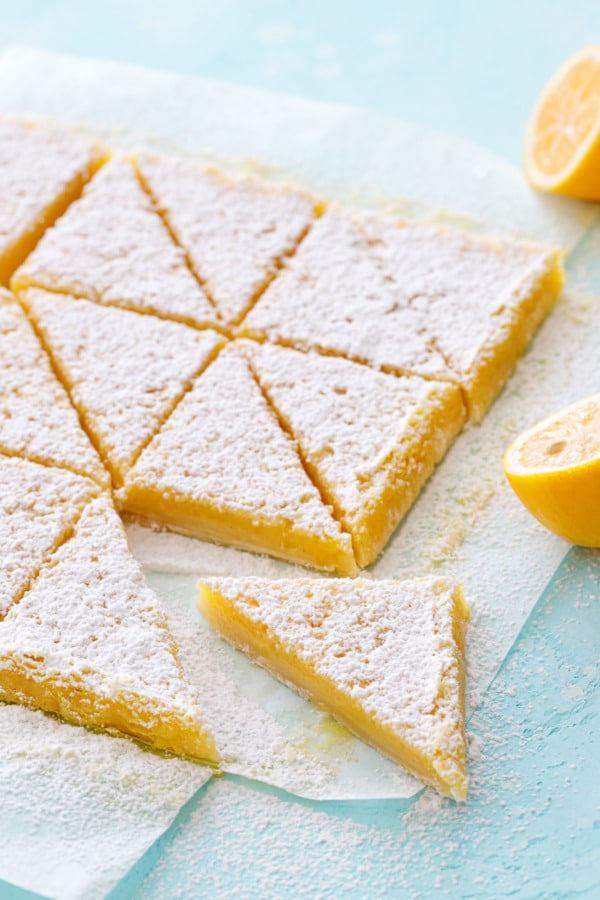 Triangular-sliced Meyer Lemon Bars on a turquoise background.