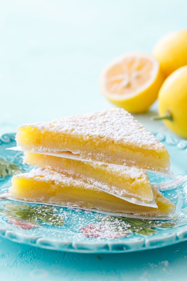 Stack of three triangular-sliced Meyer Lemon Bars on a turquoise plate