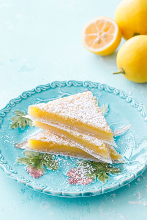 Stack of three triangular-sliced Meyer Lemon Bars on a turquoise plate