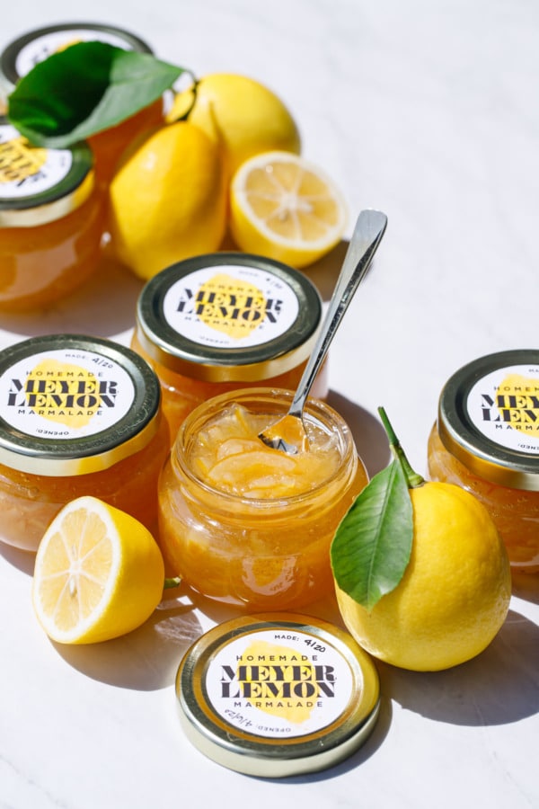 Jars of Old-Fashioned Meyer Lemon Marmalade and whole/halved lemons with leaves.