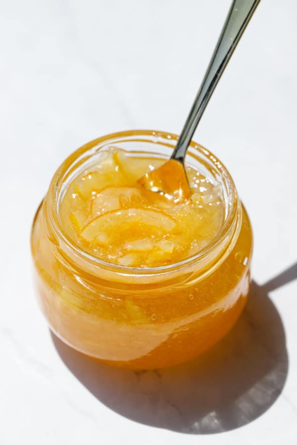 Open jar of Old-Fashioned Meyer Lemon Marmalade with gold spoon