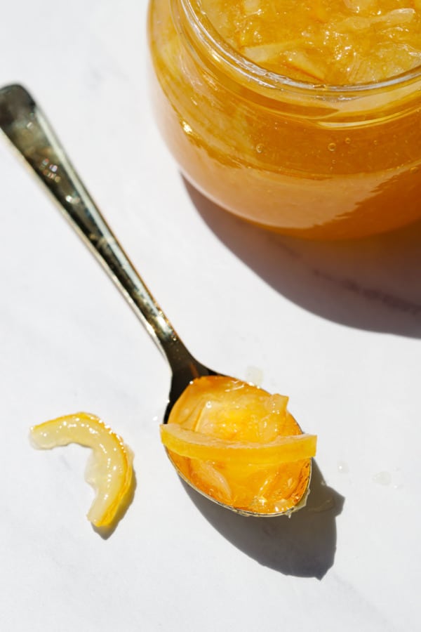 Spoonful of Old-Fashioned Meyer Lemon Marmalade and a jar on marble