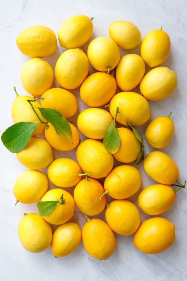 Bright yellow Meyer lemons with leaves on marble background