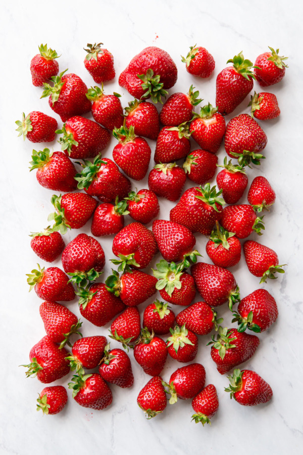 Overhead rectangle of ripe red strawberries on a marble background.