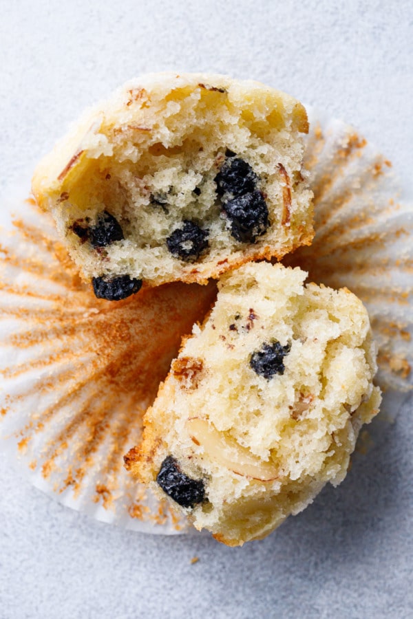 Sourdough muffin broken in half to show the crumb texture and dried blueberries and almonds inside.