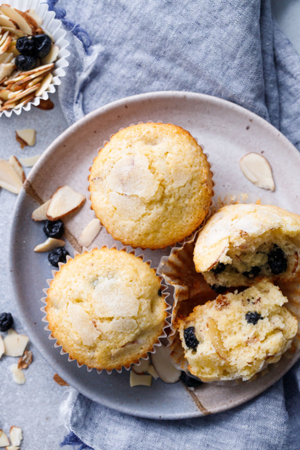 Overhead of plate with three Sourdough Muffins with dried Blueberries and Almonds scattered around