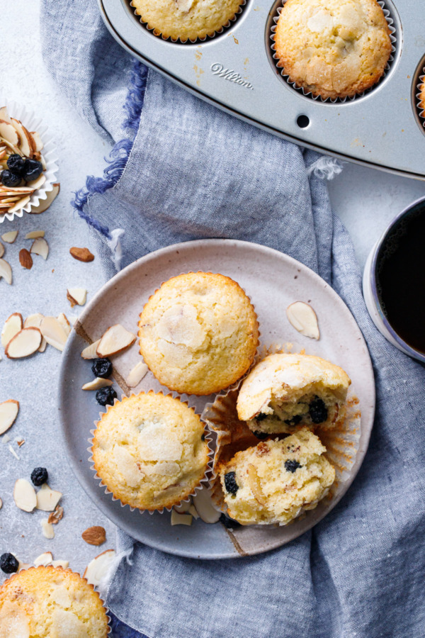 Overhead of plate of Sourdough Muffins with Blueberries and Almonds, linen napkin and muffin tin