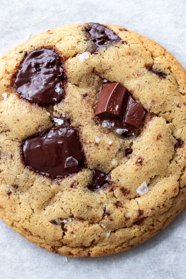 Closeup of Olive Oil Chocolate Chip Cookie, showing flaky sea salt and puddles of melty chocolate.