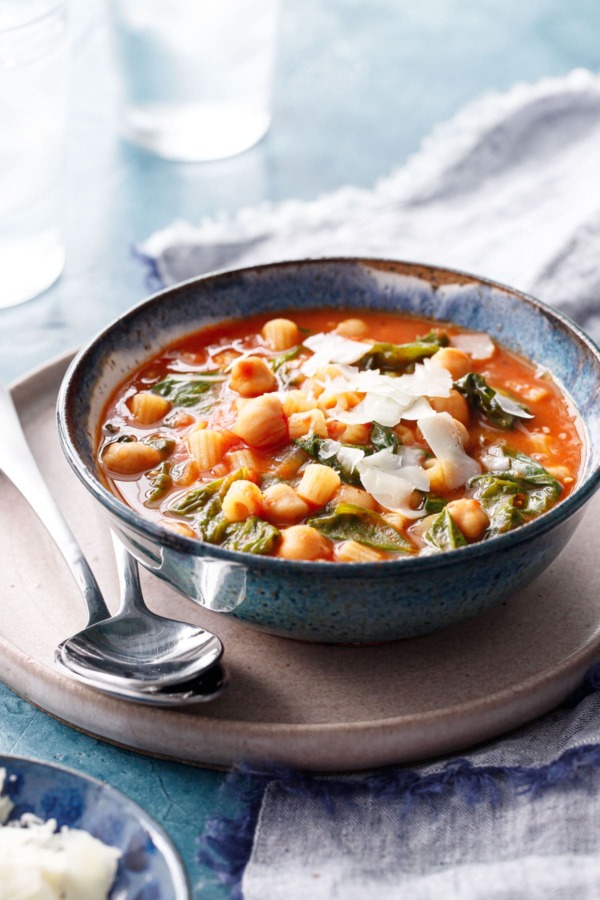 Pasta and Chickpea Stew topped with shaved pecorino, with two spoons on the side