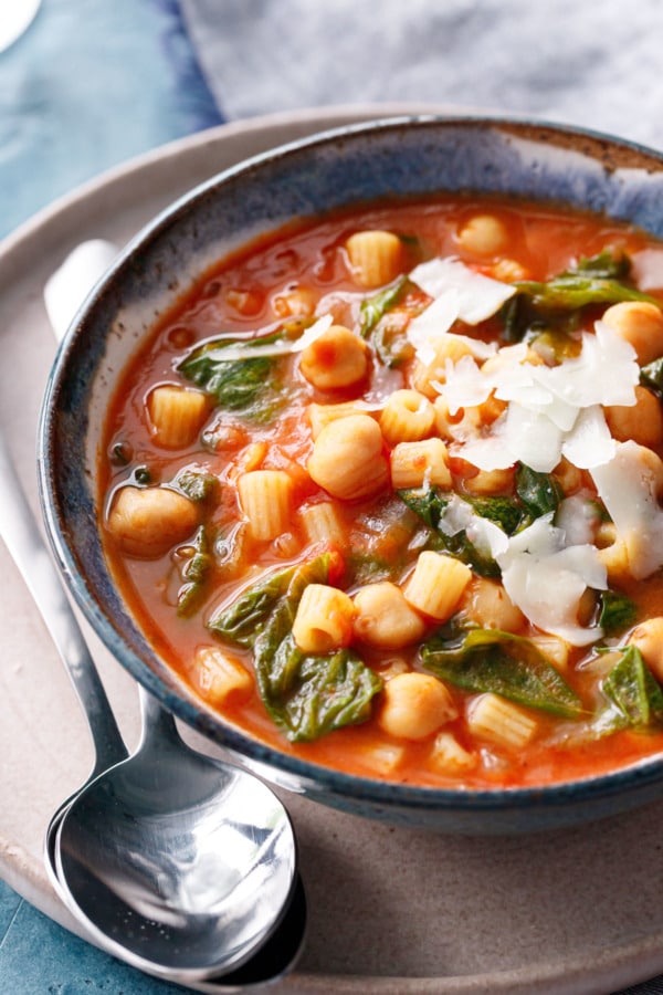 Closeup of Italian Pasta and Chickpea Stew with escarole, topped with shaved pecorino cheese