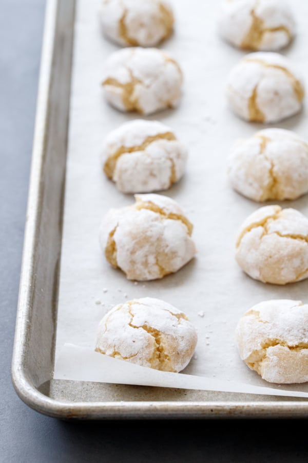 Two rows of amaretti cookies on a parchment-lined baking sheet