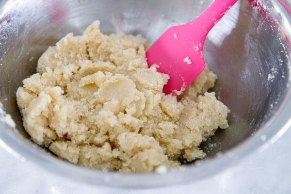 Metal bowl showing the sticky texture of amaretti cookie dough.