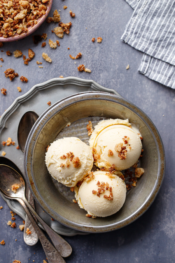 Overhead of three scoops of Sourdough Ice Cream in a metal pie tin, with sourdough breadcrumbs and spoons.