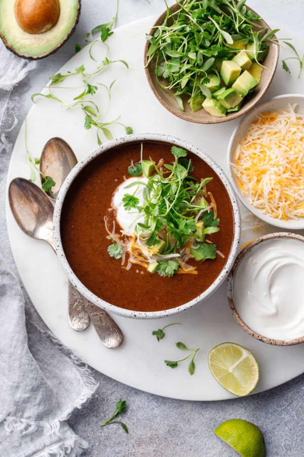 Overhead bowl of black bean soup with bowls of toppings on the side