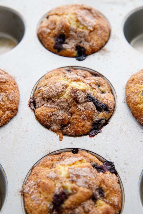 Closeup of baked blueberry muffins with sugar topping in a silver muffin tin