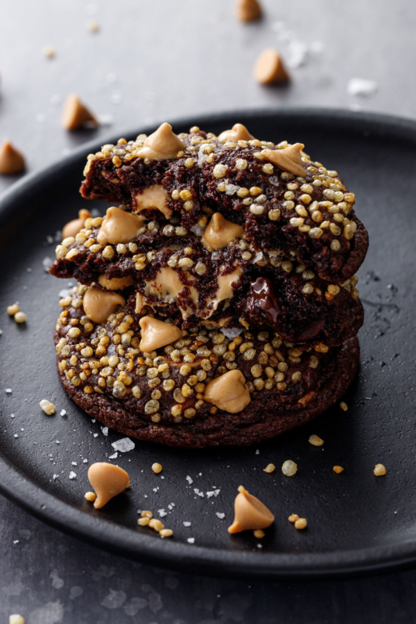 Stack of cookies, one broken in half to show the gooey center and melty peanut butter chips