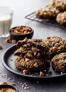 Chocolate cookies topped with puffed quinoa, on a plate with a glass of milk