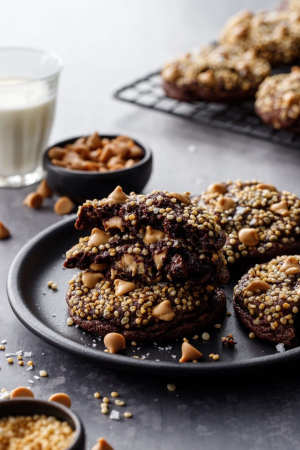 Chocolate cookies topped with puffed quinoa, on a plate with a glass of milk