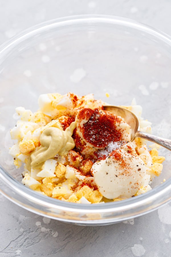 Egg salad ingredients in a bowl waiting to be mixed