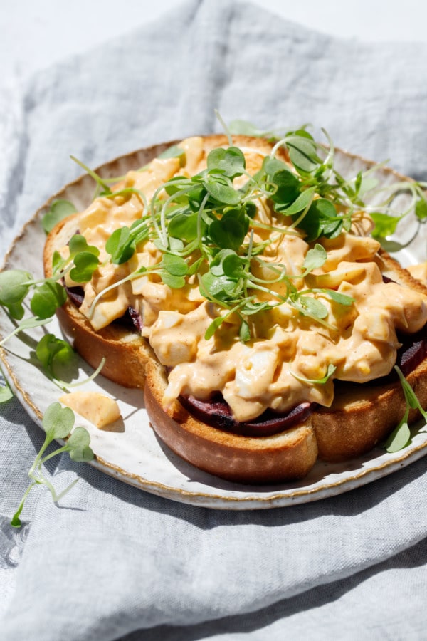 Open face egg salad sandwich in direct sunlight