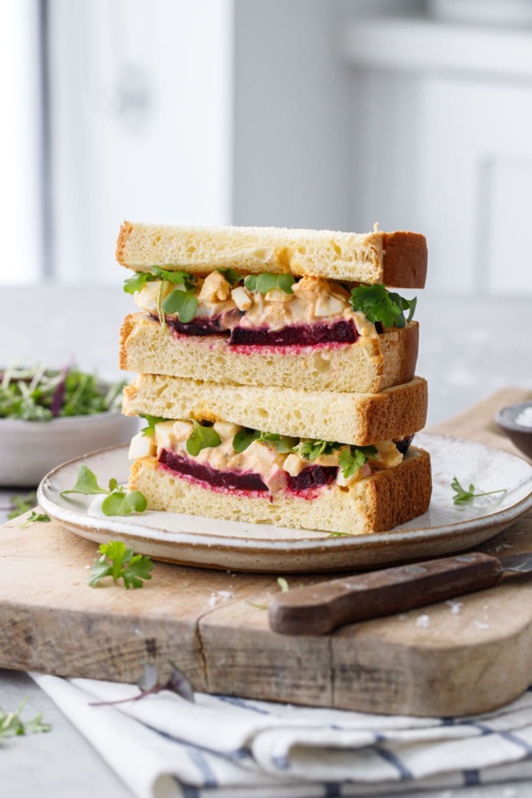 Egg salad sandwich cut in half, showing the layers of beet and egg