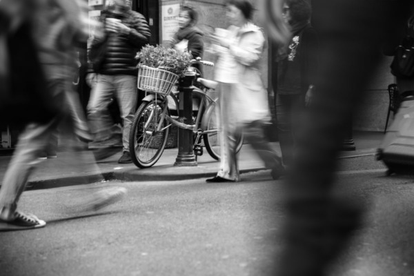 Bike with flower basket, blurred people in motion, black and white.