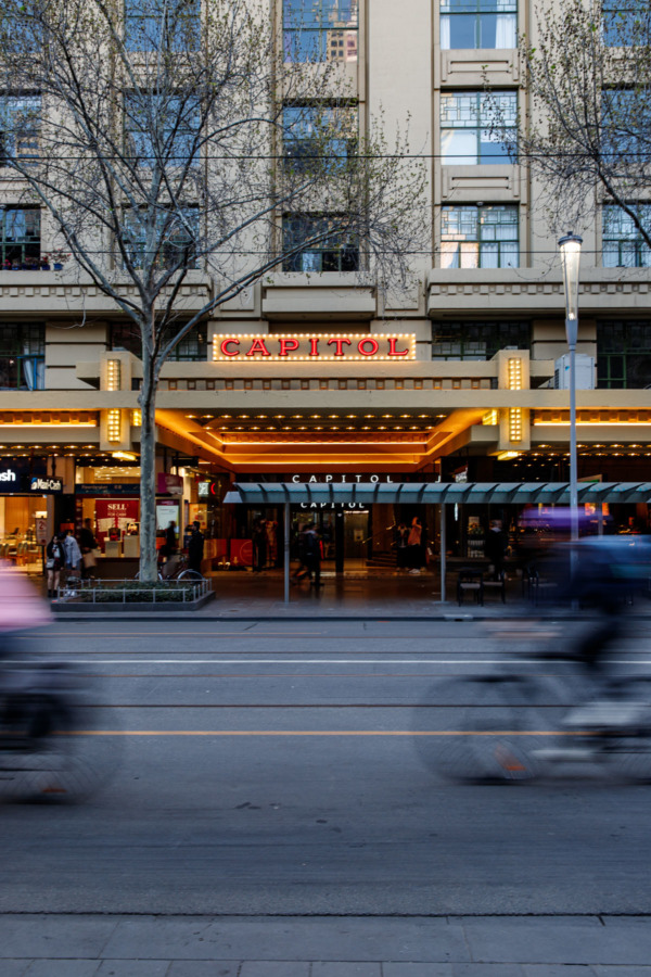 Neon lights of the Capitol Theatre in Melbourne, Australia, with motion blur bikers moving by on the street