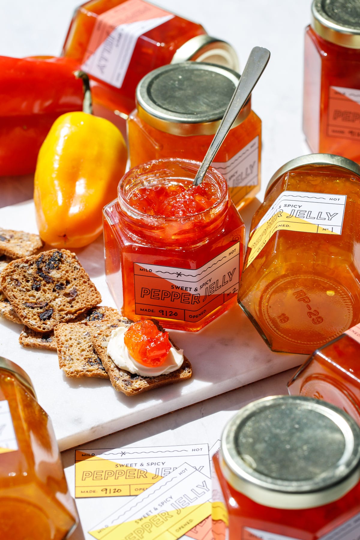 Assorted jars of orange and red pepper jelly with crackers and cream cheese