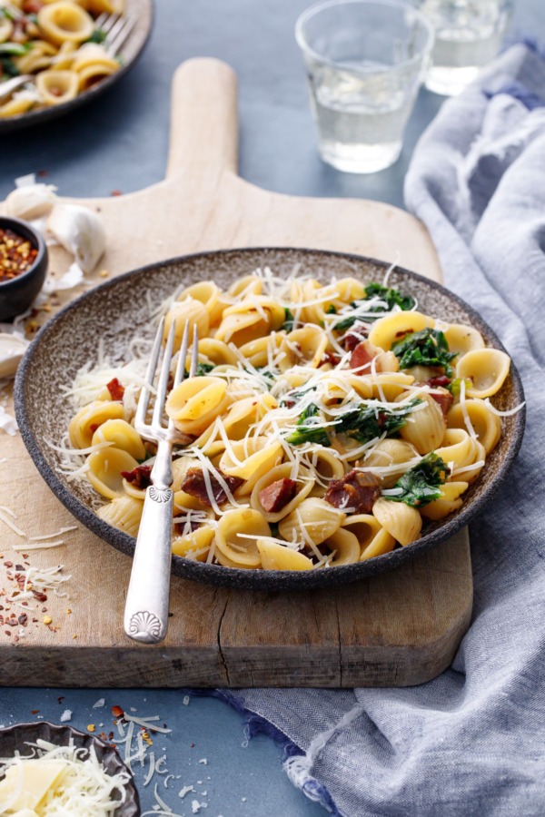 Bowl of orecchiette on a vintage wood board with a silver fork