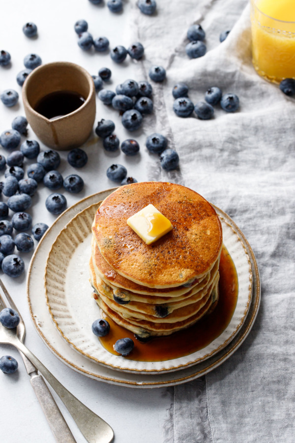 Stack of blueberry pancakes with fresh blueberries scattered around