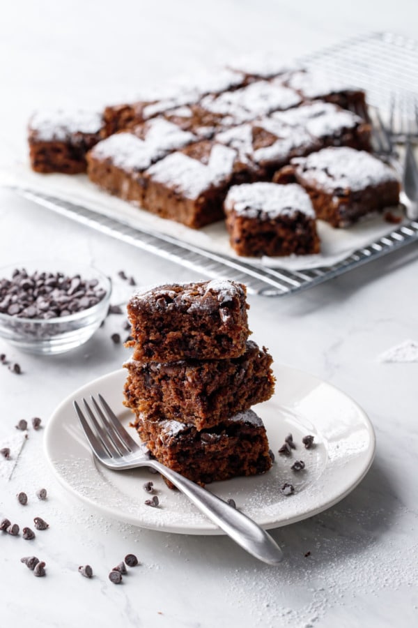 Stack of cake pieces on a plate, with rest of the cake in the background