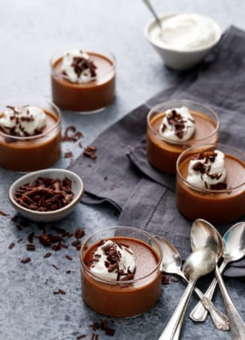 Glass ramekins filled with Chocolate Pumpkin Pot de Creme on a dark gray background