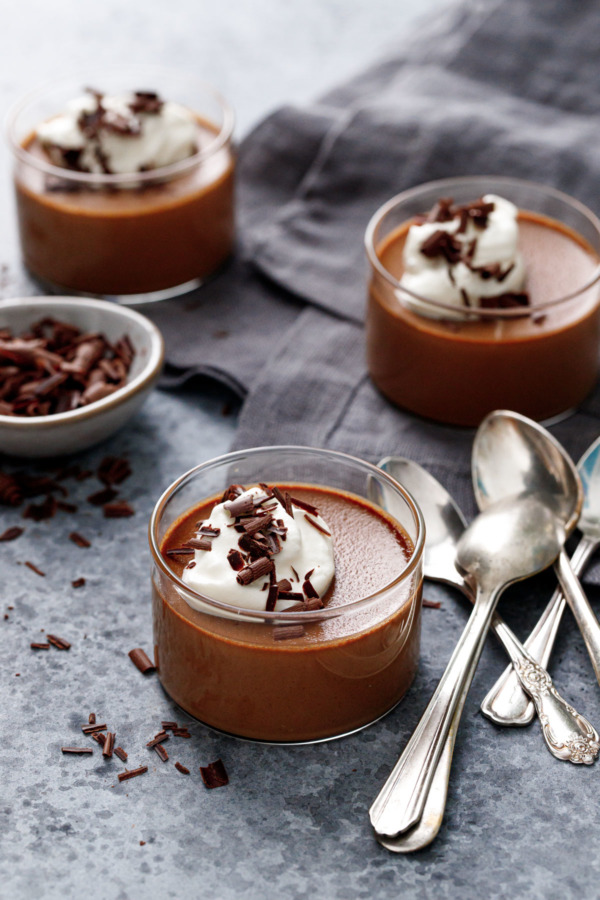 Chocolate Pumpkin Pot de Creme in glass ramekins, on gray background with a gray linen napkin and silver spoons