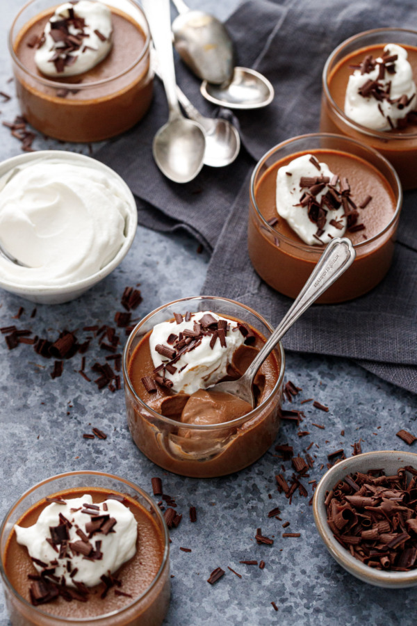 Chocolate Pumpkin Pot de Creme in glass ramekins, with bowls of whipped cream and shaved chocolate for topping