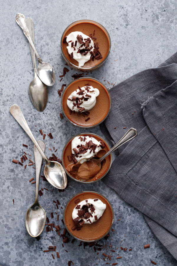 Overhead, row of 4 Chocolate Pumpkin Pot de Creme in glass ramekins with silver spoons