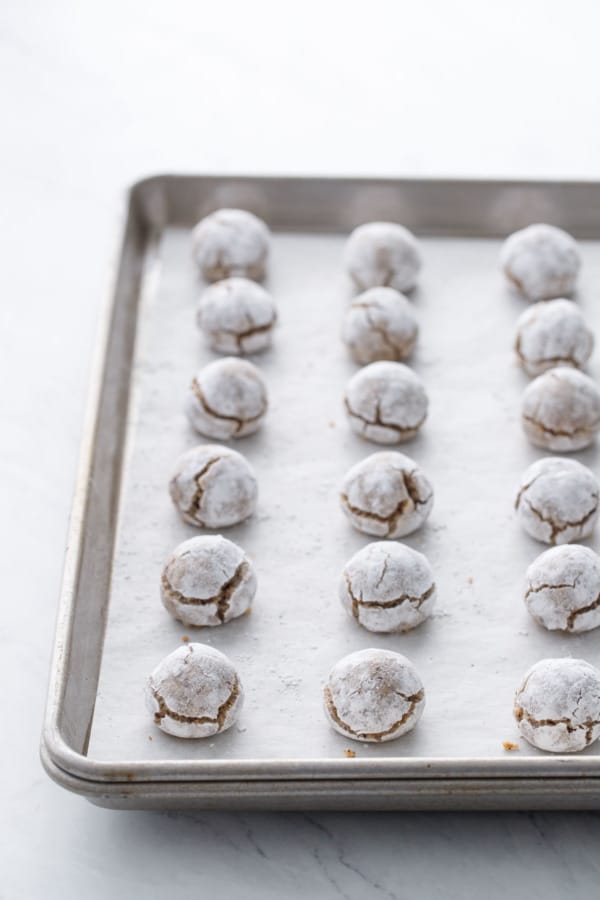 Rows of baked hazelnut amaretti cookies on a baking sheet