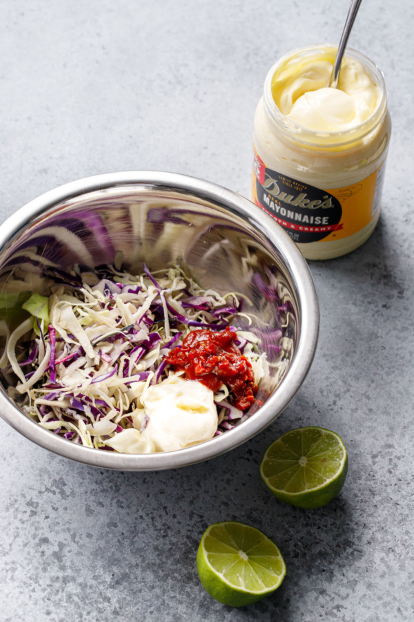 Ingredients for chipotle slaw in a metal bowl, with jar of Duke's mayonnaise