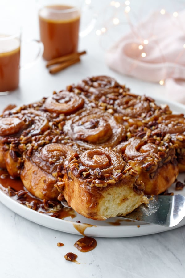 Platter of gooey sticky buns with pecans, cups of hot buttered rum and twinkle lights