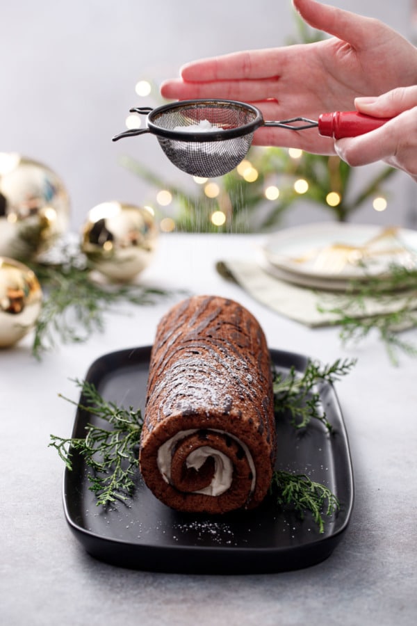 Dusting the Chocolate Chestnut Christmas Cake Roll with powdered sugar